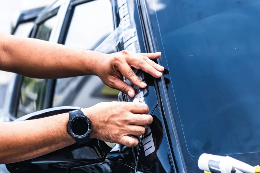 Two hands applying tint film to a car window.