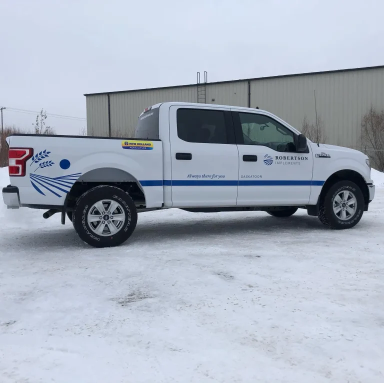 A white pickup truck with blue lettering and graphics on the side and rear box.