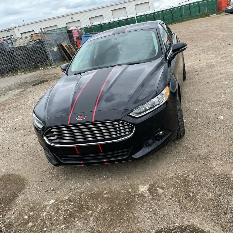 A black sedan with black and red stripes going down the center