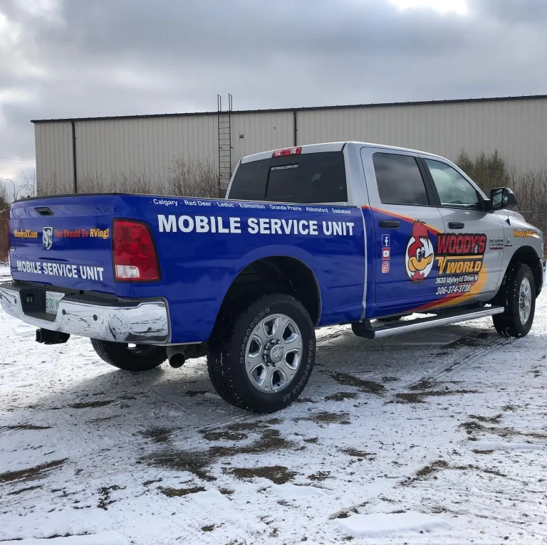 A pickup truck with company themed wrap logos on the side and rear cab.