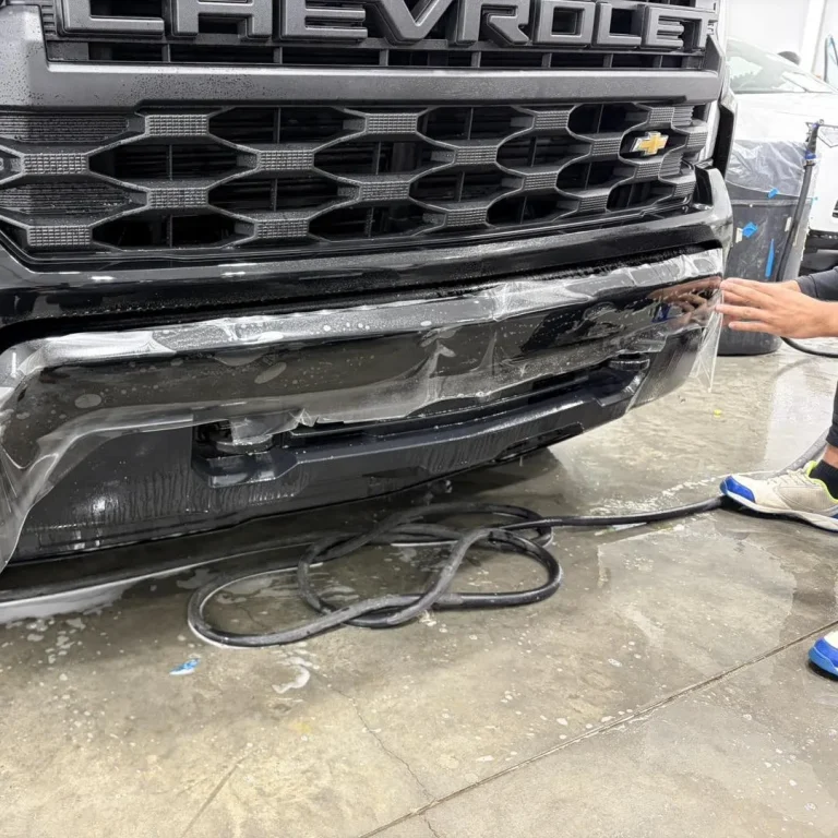 Man applying paint protection film to the bumper of a truck.