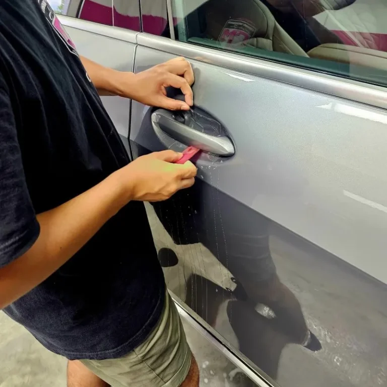 May applying paint protection film to the door handle bar area of a car.