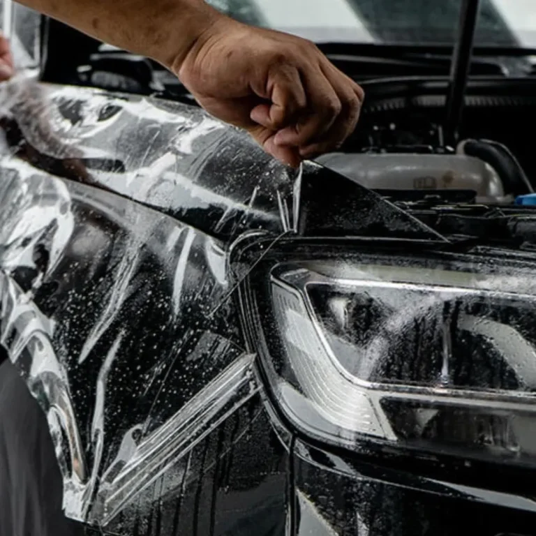 Man applying PPF to the front quarter of a car.