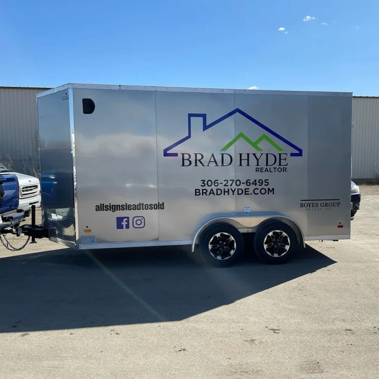 A silver trailer with company logo and contact information on the side.