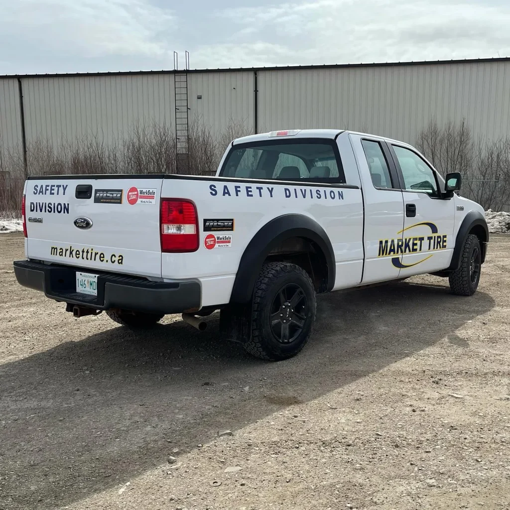 A white truck wrapped with company logo and lettering on the side and rear.