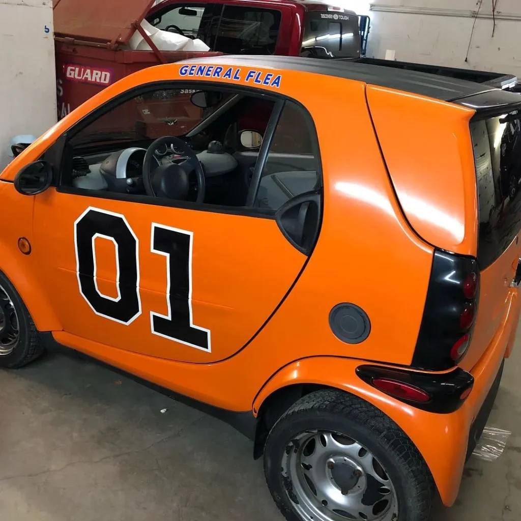 A Smartcar with orange vinyl wrap.